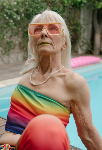 Elderly woman sitting at pool looking intense and hip.