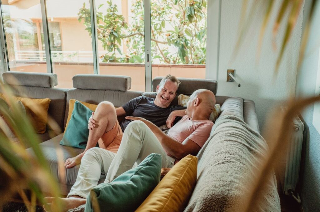 Gay couple lying on the couch laughing.